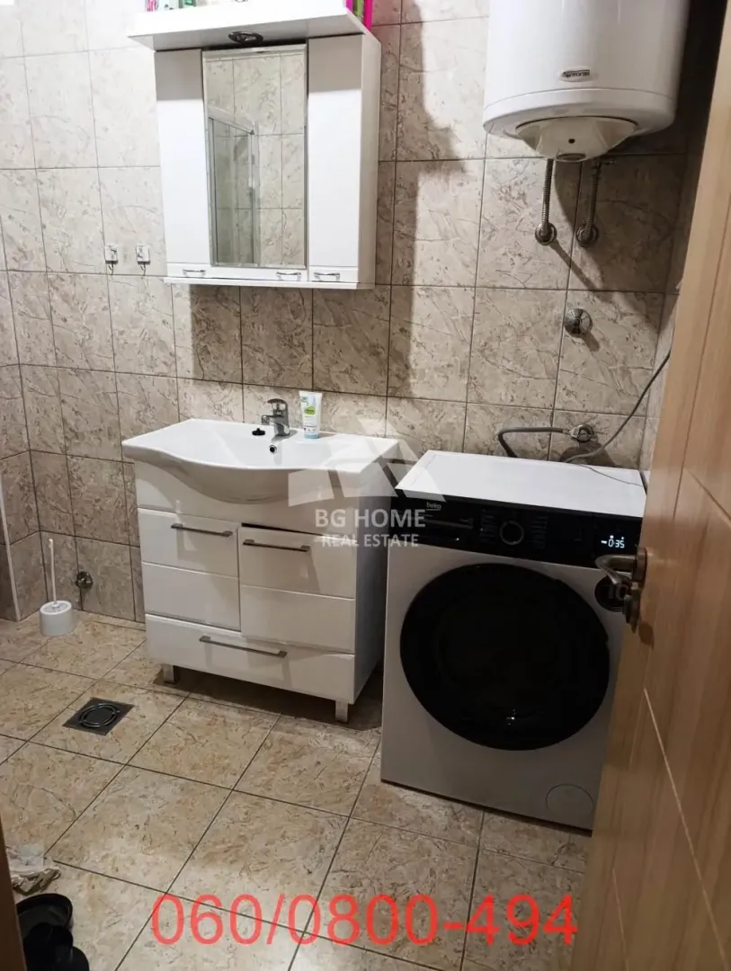 Kupatilo sa umivaonikom, ogledalom i mašinom za veš.