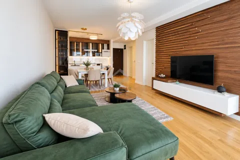 Modern living room with a green sectional sofa and a wooden wall paneling. - image 2