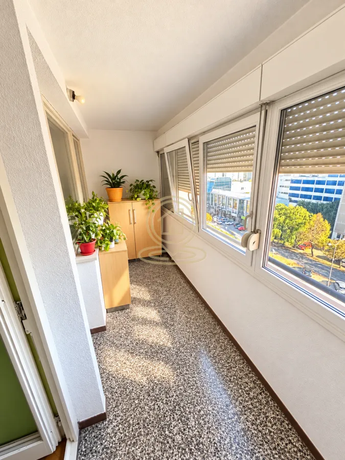 Zastakljeni balkon sa prozorima i pogledom na ulicu.