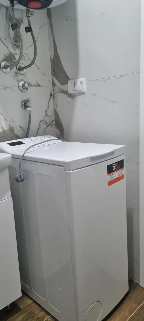 Kupatilo sa veš mašinom i keramičkim pločicama.
