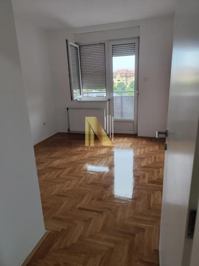 Prazna soba sa parketom i izlazom na terasu.