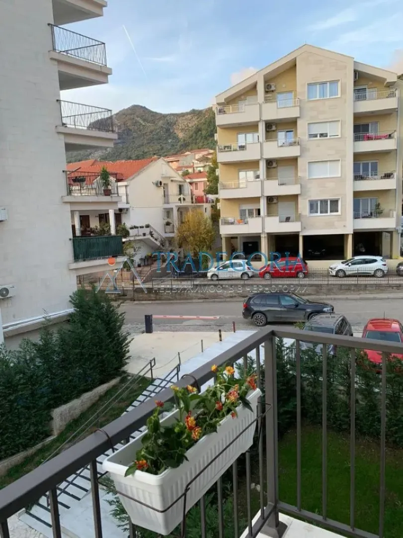 Pogled sa balkona na okolne zgrade, ulicu i brda u pozadini.