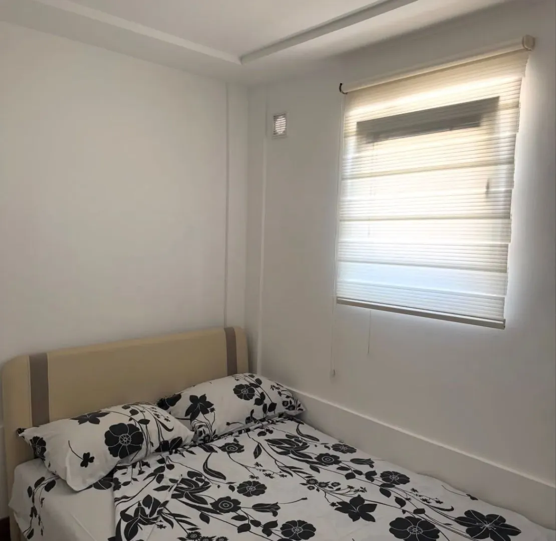 Furnished bedroom with a bed and a window with blinds.