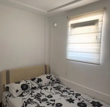Furnished bedroom with a bed and a window with blinds. - image 8