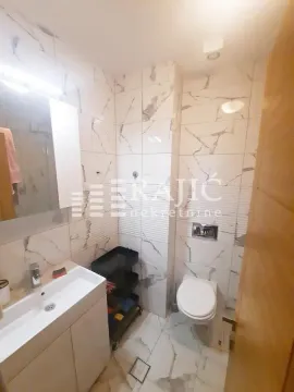 Small bathroom with a sink, toilet, and marble tiles. - image 7