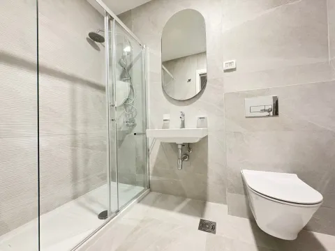Moderno opremljeno kupatilo sa tuš kabinom, umivaonikom i visećom šoljom. - image 4