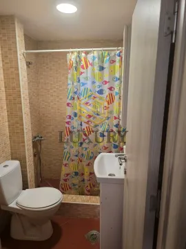 Smaller bathroom with a shower enclosure, washbasin, and toilet. - image 6