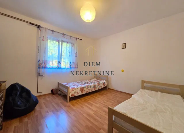 Dječija soba sa dva kreveta i laminatom na podu.