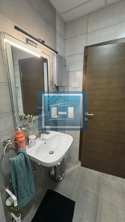Smaller bathroom with a sink, mirror, and tiling.
