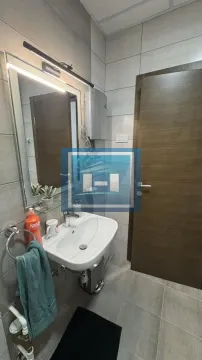 Smaller bathroom with a sink, mirror, and tiling. - image 15