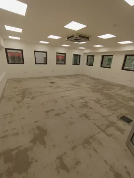 Spacious empty room with an unfinished floor and multiple windows. - image 6