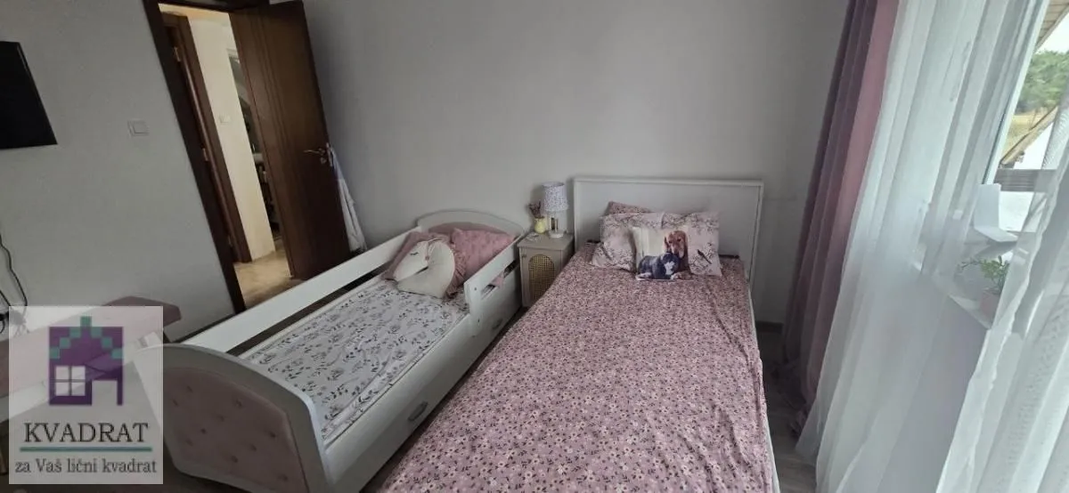 Dečja spavaća soba sa dva kreveta i prozorom.