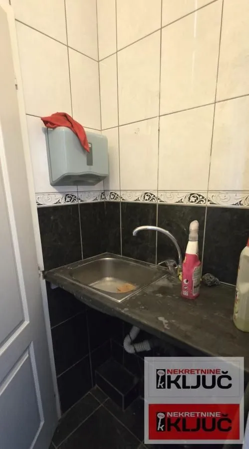 Small kitchen with a sink and wall tiles.
