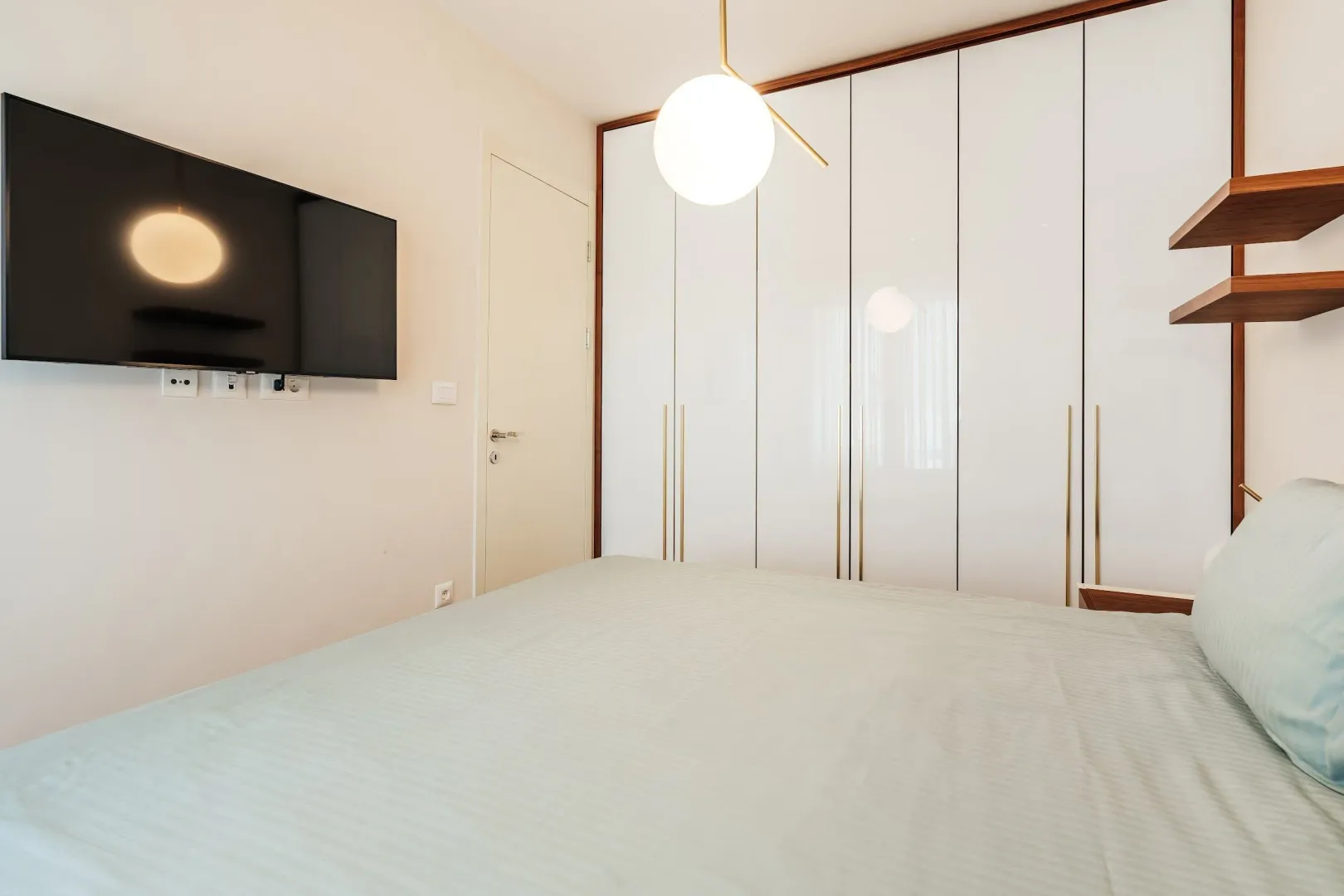Modern bedroom with a double bed, built-in wardrobe, and wall-mounted TV.