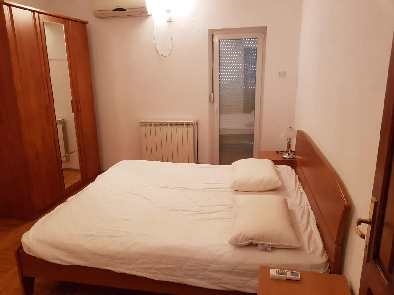 Simply furnished bedroom with a double bed and a wooden wardrobe.