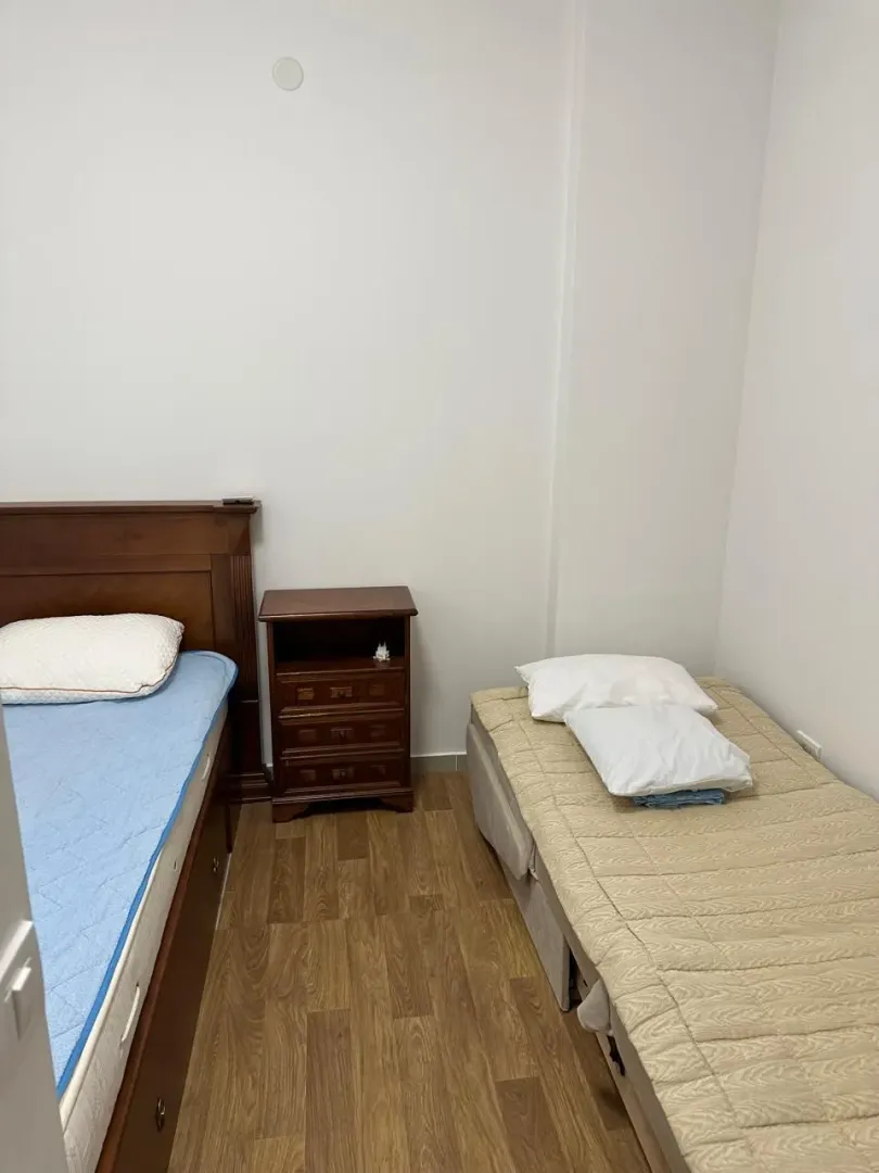 Spavaća soba sa dva kreveta i noćnim stočićem.