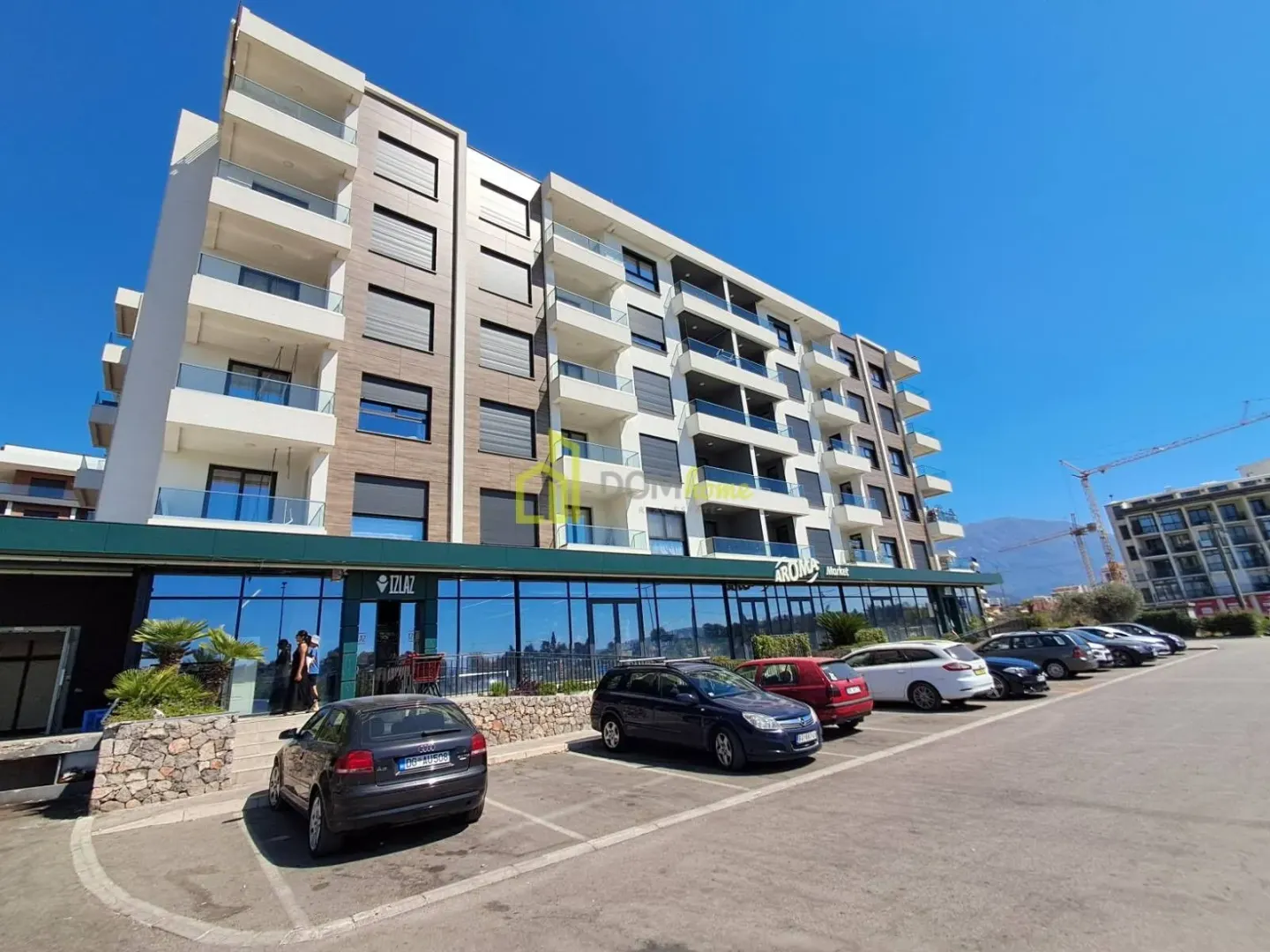 Exterior view of a modern residential building with a parking lot in front.