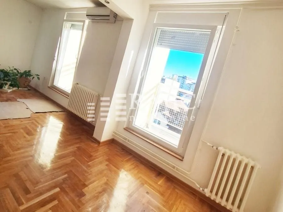 Living room with parquet flooring and windows.