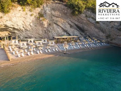 Pogled iz vazduha na uređenu plažu sa ležaljkama i suncobranima ispod stijene. - image 30