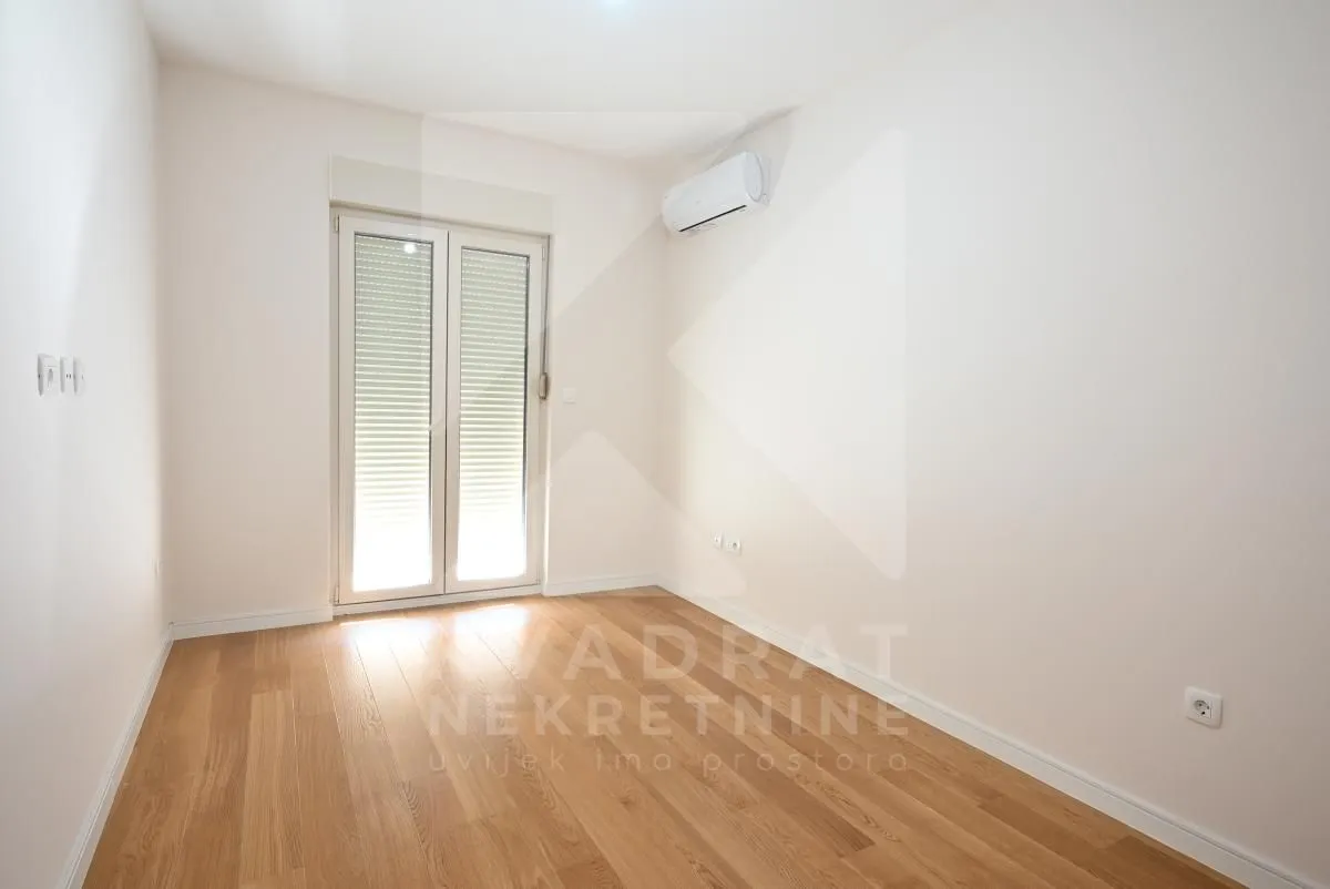 Empty room with hardwood flooring and balcony doors.