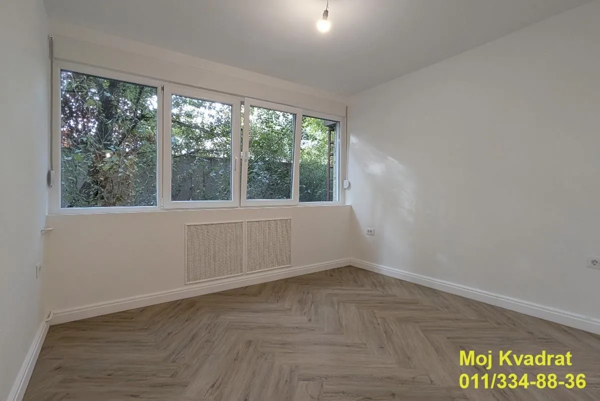 Prazna soba sa belim zidovima i drvenim podom.
