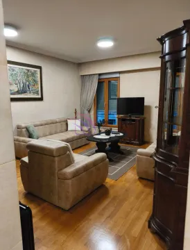 Dnevna soba opremljena garniturom, stočićem, televizorom i drvenim namještajem. - image 4