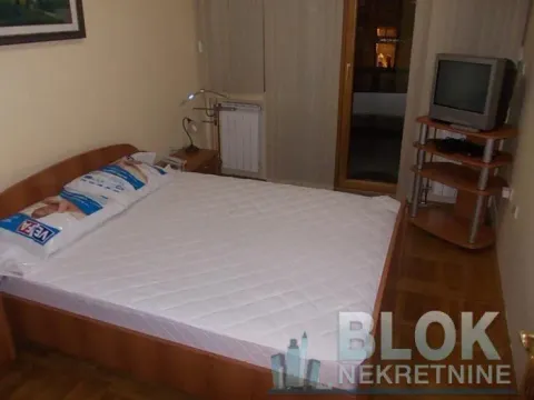 Furnished bedroom with a double bed, bedside table, and television. - image 5