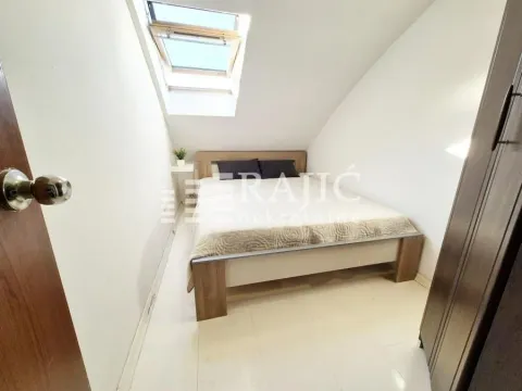 Attic bedroom with a bed and a roof window. - image 2