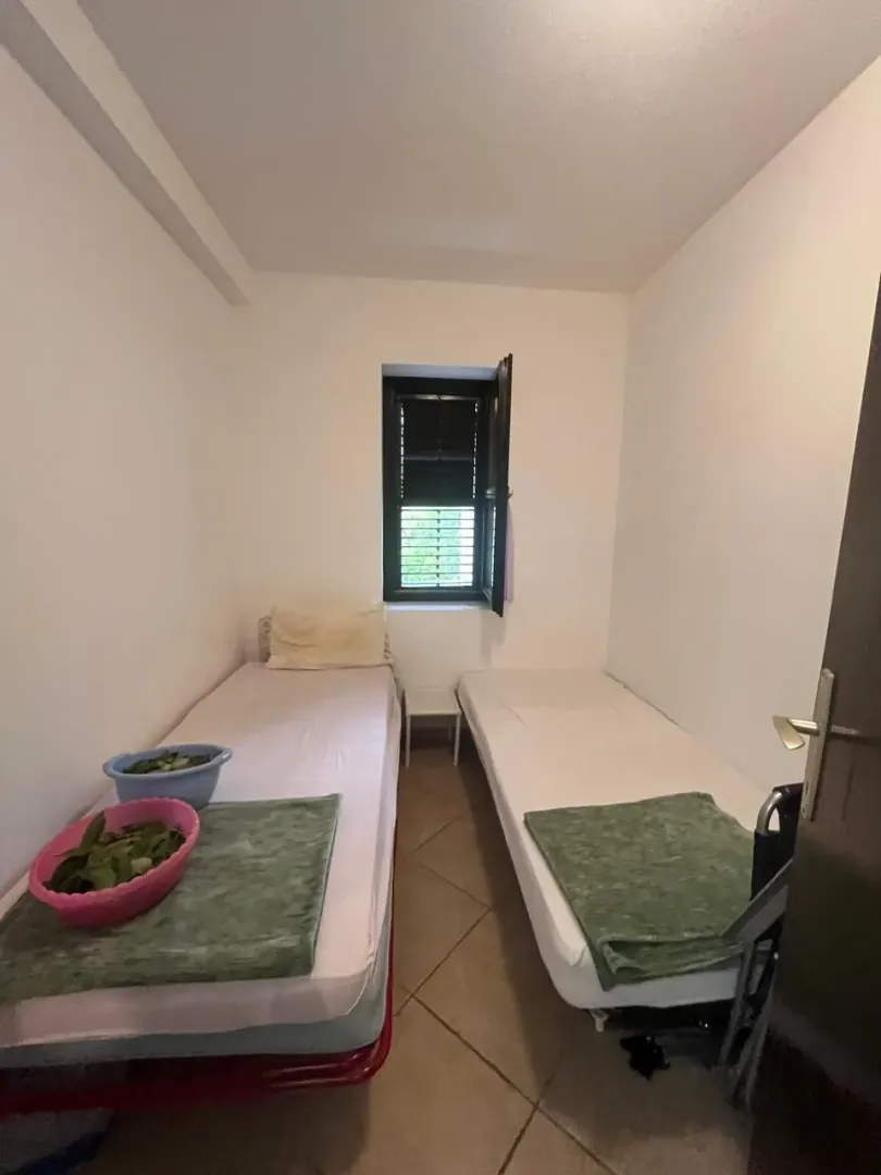 Manja spavaća soba sa dva singl kreveta i malim prozorom.