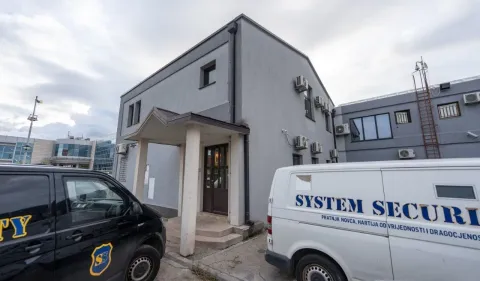 Exterior view of the building with an entrance and parked security vehicles. - image 11
