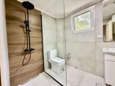 Moderne kupatilo sa tuš kabinom, staklenom pregradom i crnim slavinama. - image 8