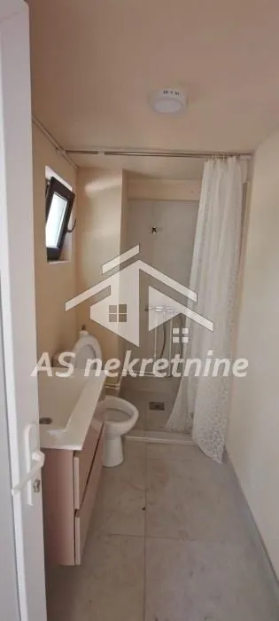 Smaller bathroom with a shower cabin, washbasin, and toilet.