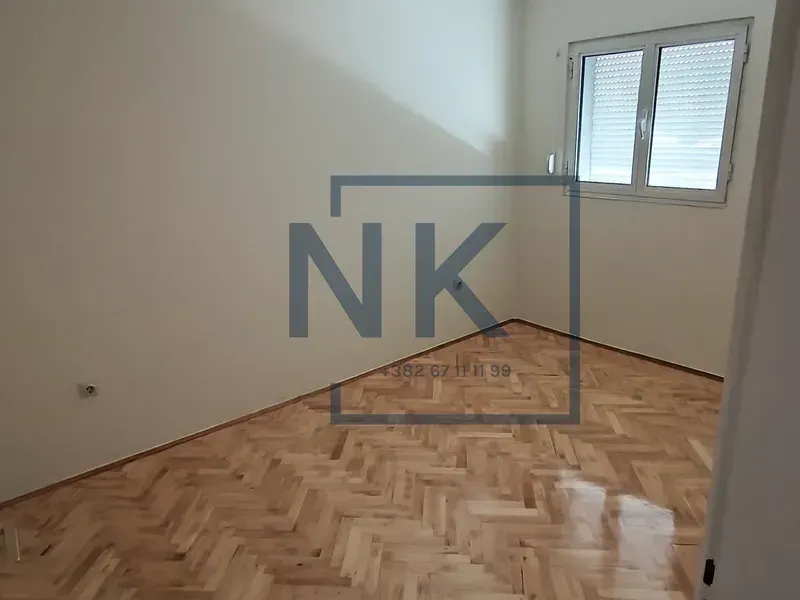 Empty room with parquet flooring and a window.