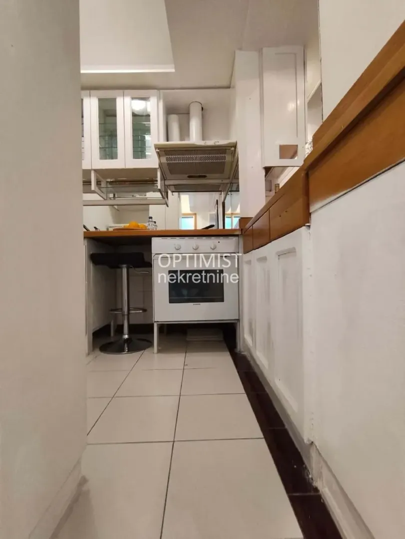 Pogled na manju kuhinju sa belim elementima i šporetom.