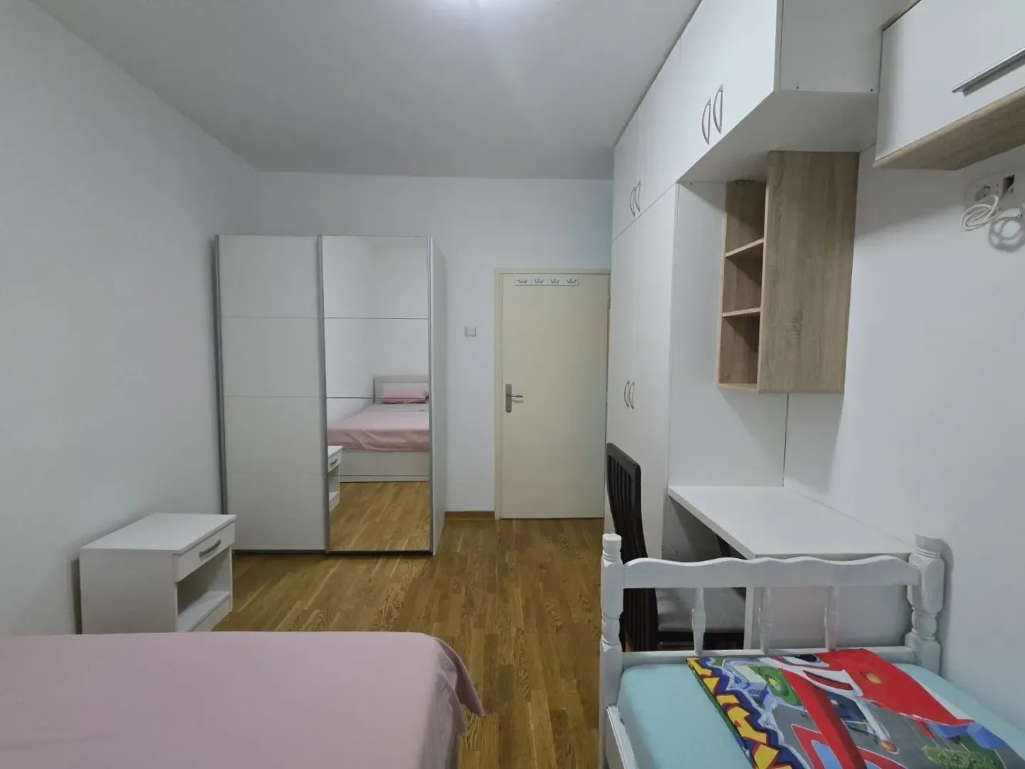 Children's bedroom with beds, a desk, and wardrobes.