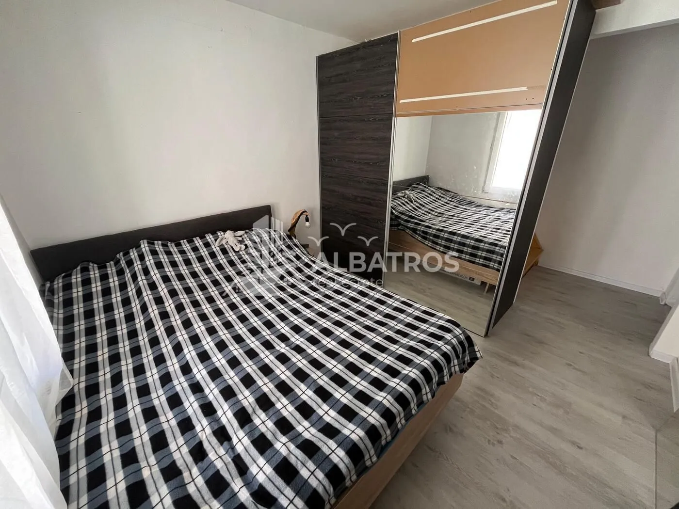 Furnished bedroom with a double bed and a large wardrobe with a mirror.