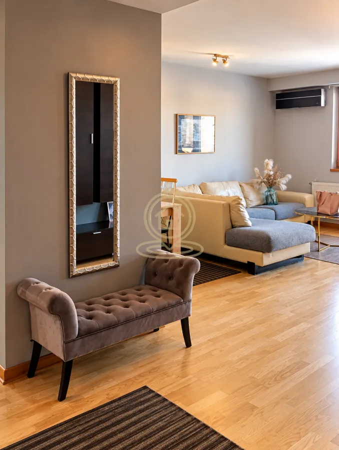 View from the hallway towards the living room with a sectional sofa and a wall mirror.
