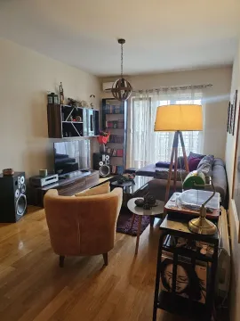 Furnished living room with a sofa, TV, and bookshelves. - image 2