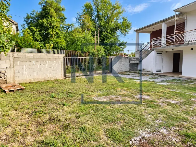 Yard of the house with a fence, gate, and greenery.