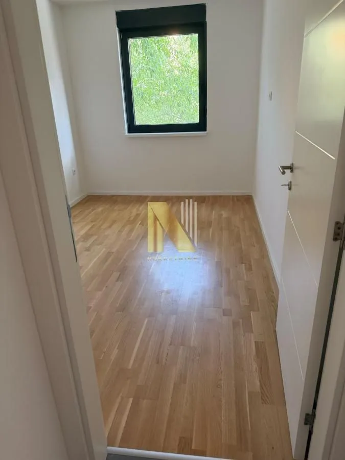 Prazna soba sa parketom i jednim prozorom.