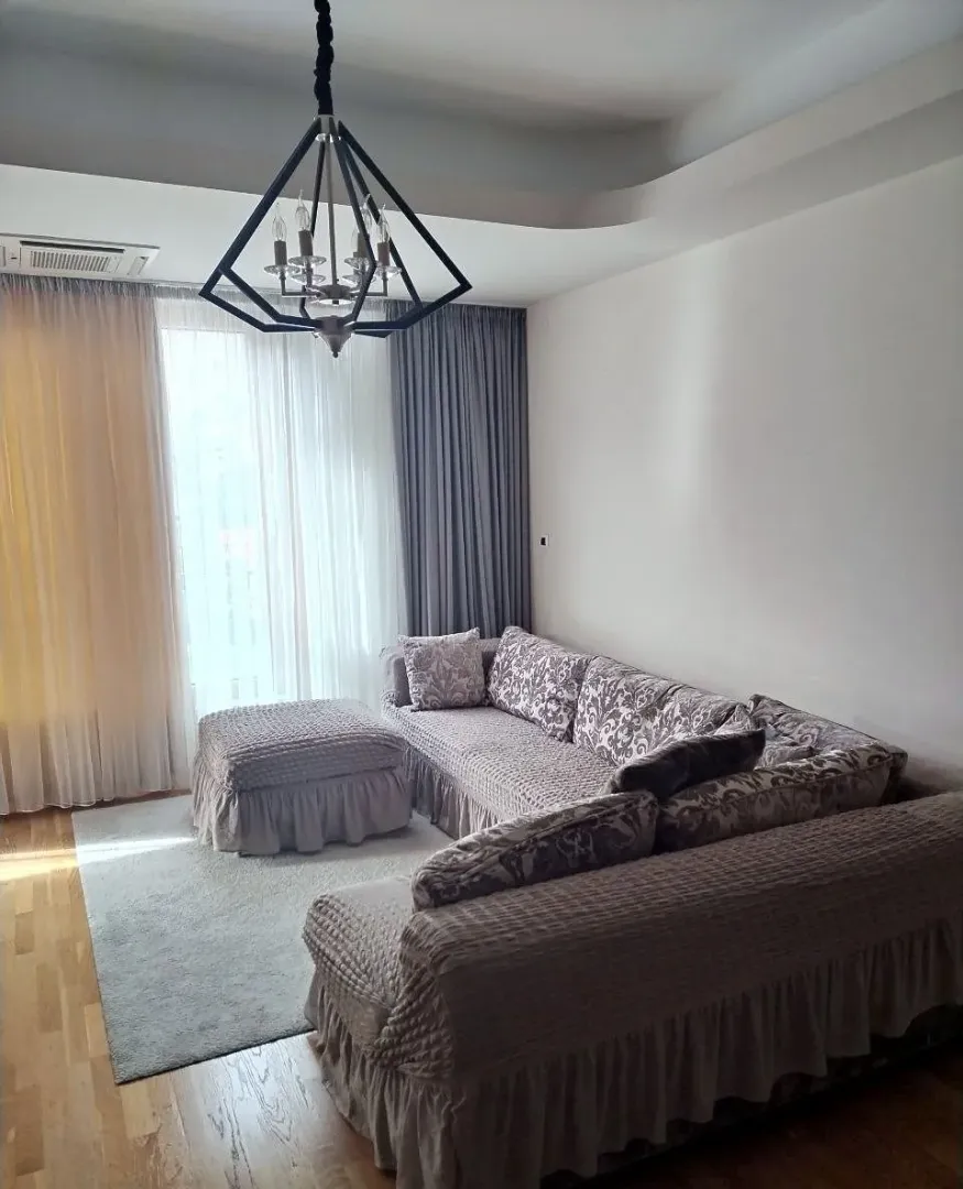 Comfortable living room with a corner sofa and modern chandelier.