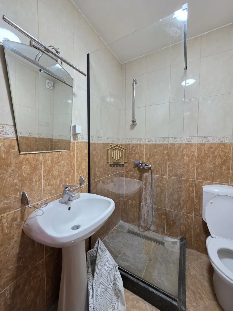 Bathroom equipped with a washbasin, walk-in shower with a glass partition, and a toilet.