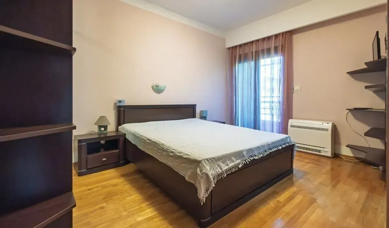 Spavaća soba sa bračnim krevetom, noćnim stočićima i izlazom na balkon.