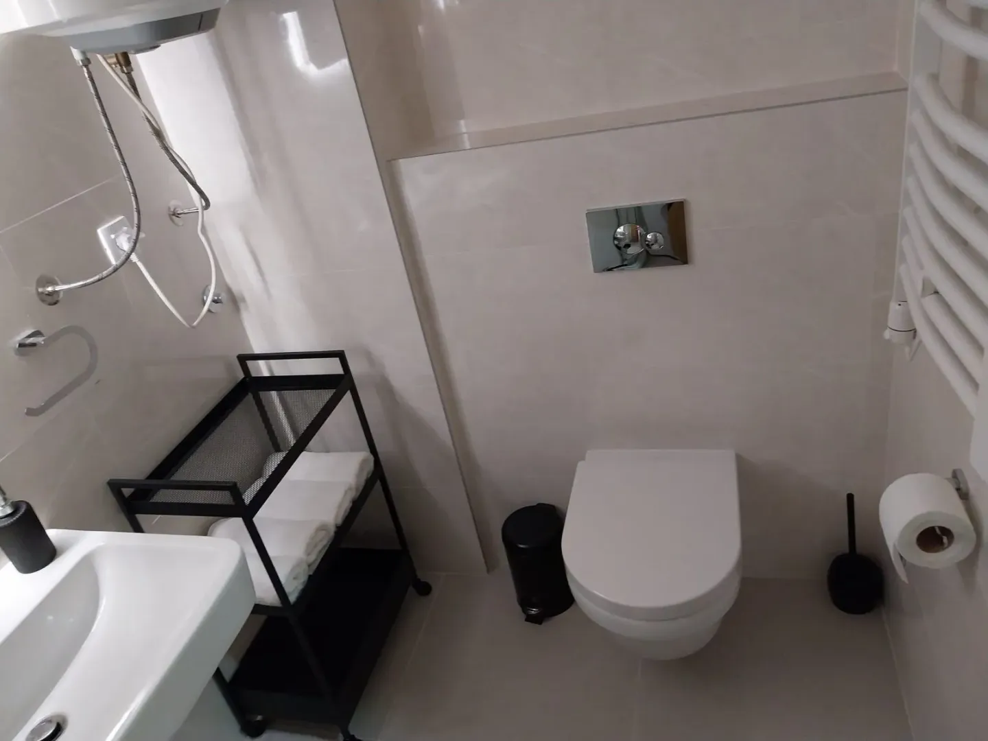 Modern bathroom with a wall-mounted toilet and shelf.