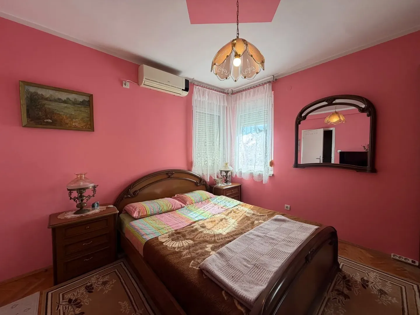 Furnished bedroom with a double bed and pink walls.