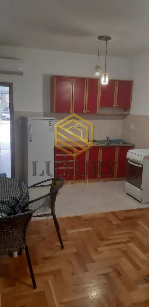 Manja kuhinja sa crvenim elementima i trpezarijskim stolom u prvom planu.