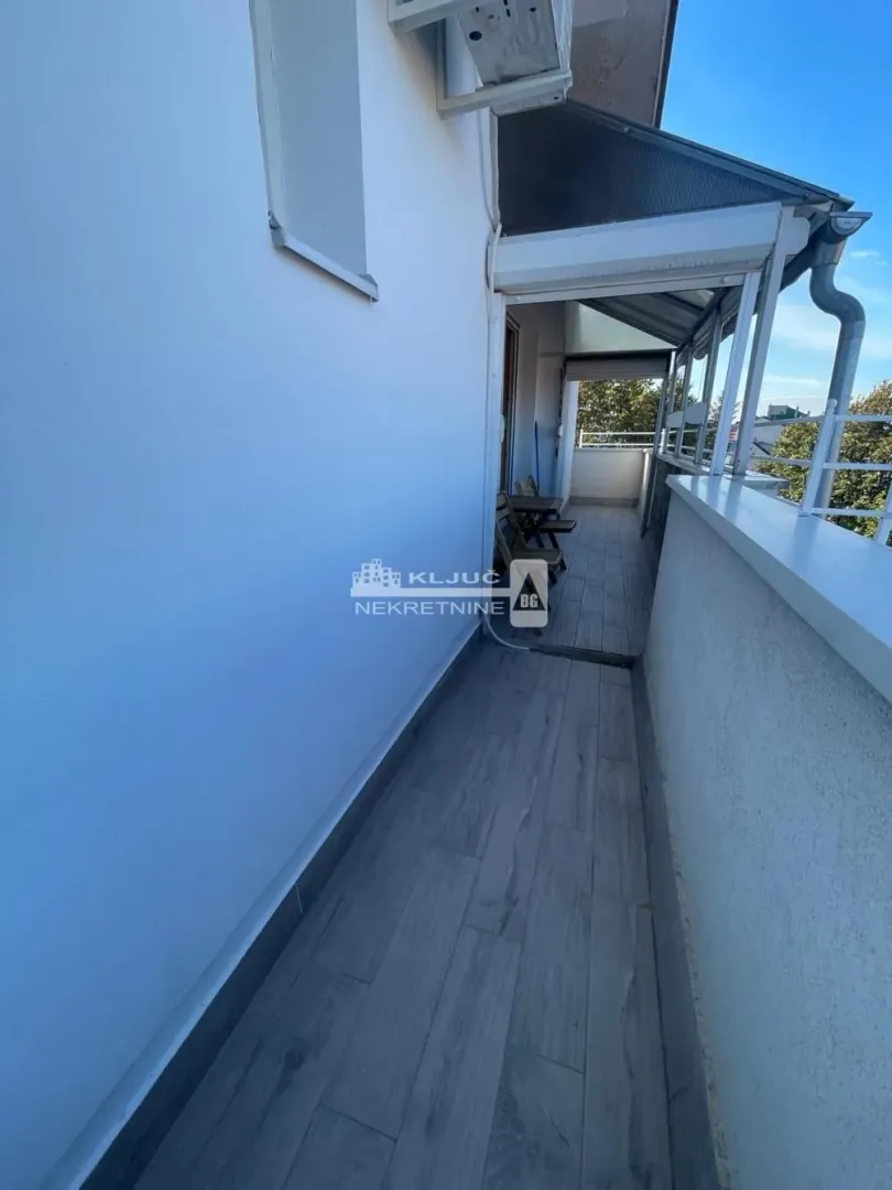 Pogled na prostrani natkriveni balkon sa popločanim podom i ogradom.