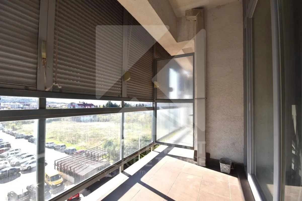 Covered balcony with a glass railing and a view of the parking lot and surroundings.