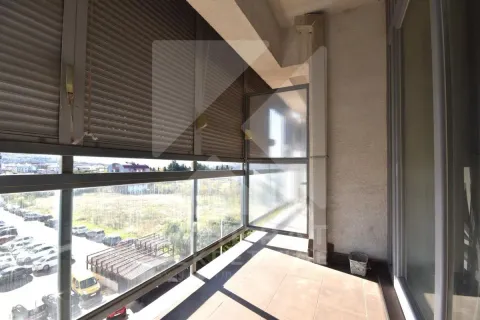 Covered balcony with a glass railing and a view of the parking lot and surroundings. - image 10