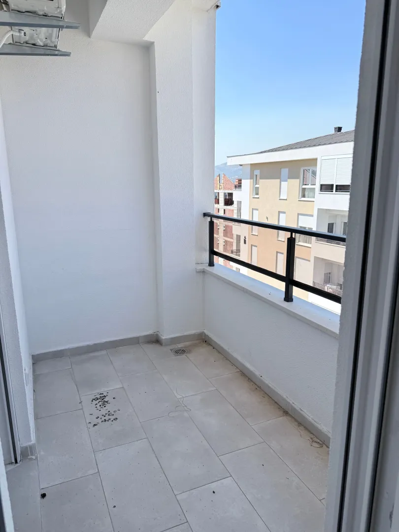 Prazan svijetli balkon sa pogledom na okolne zgrade.